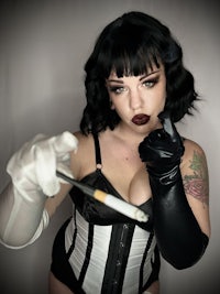 a woman in a black and white corset holding a cigarette